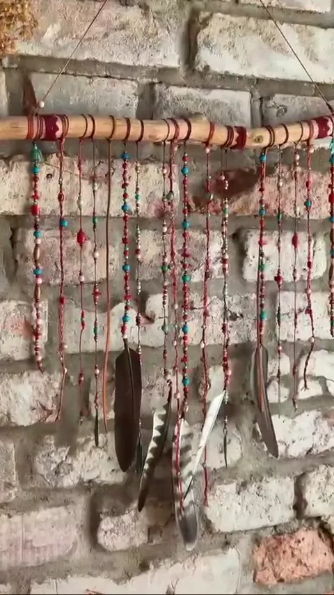 Lapač snů z korálků a per na cihlové zdi sálu